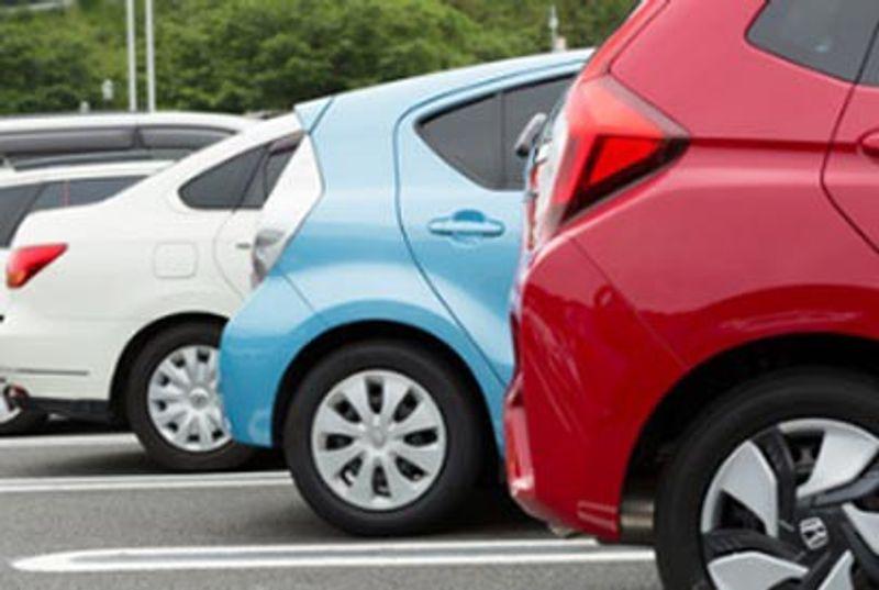 Three compact cars—red, blue, and white—parked side by side in marked parking spaces.