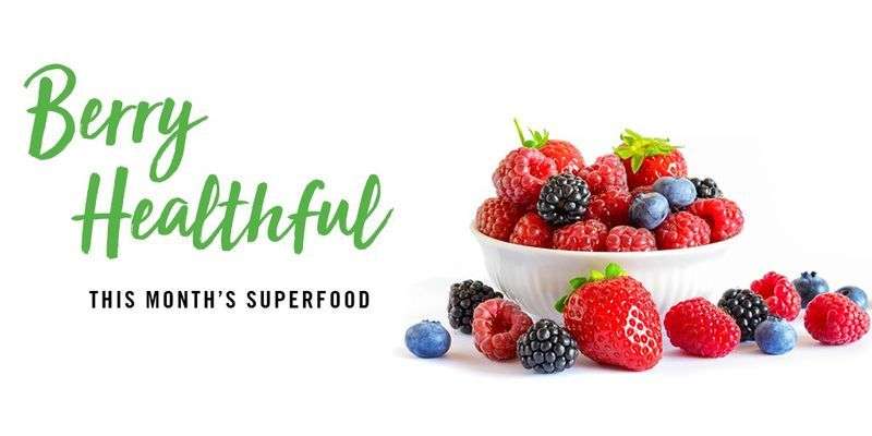 Berry Healthful, this month's superfood with a white bowl filled with strawberries, raspberries, blackberries, and blueberries.