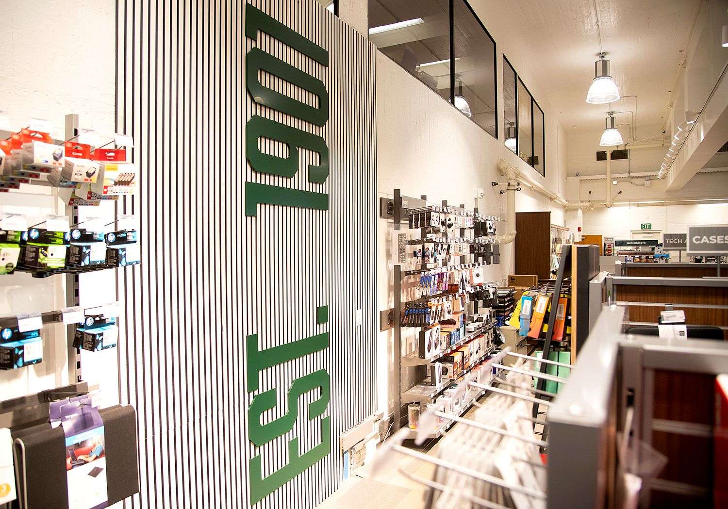Tech accessories displayed on shelves in a well-lit store aisle with a large "ESL 1901" sign on a striped wall.
