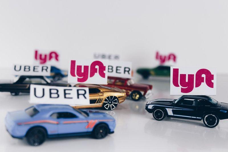 Toy cars with small signs on their roofs showing "UBER" and "lyft" logos alternating.