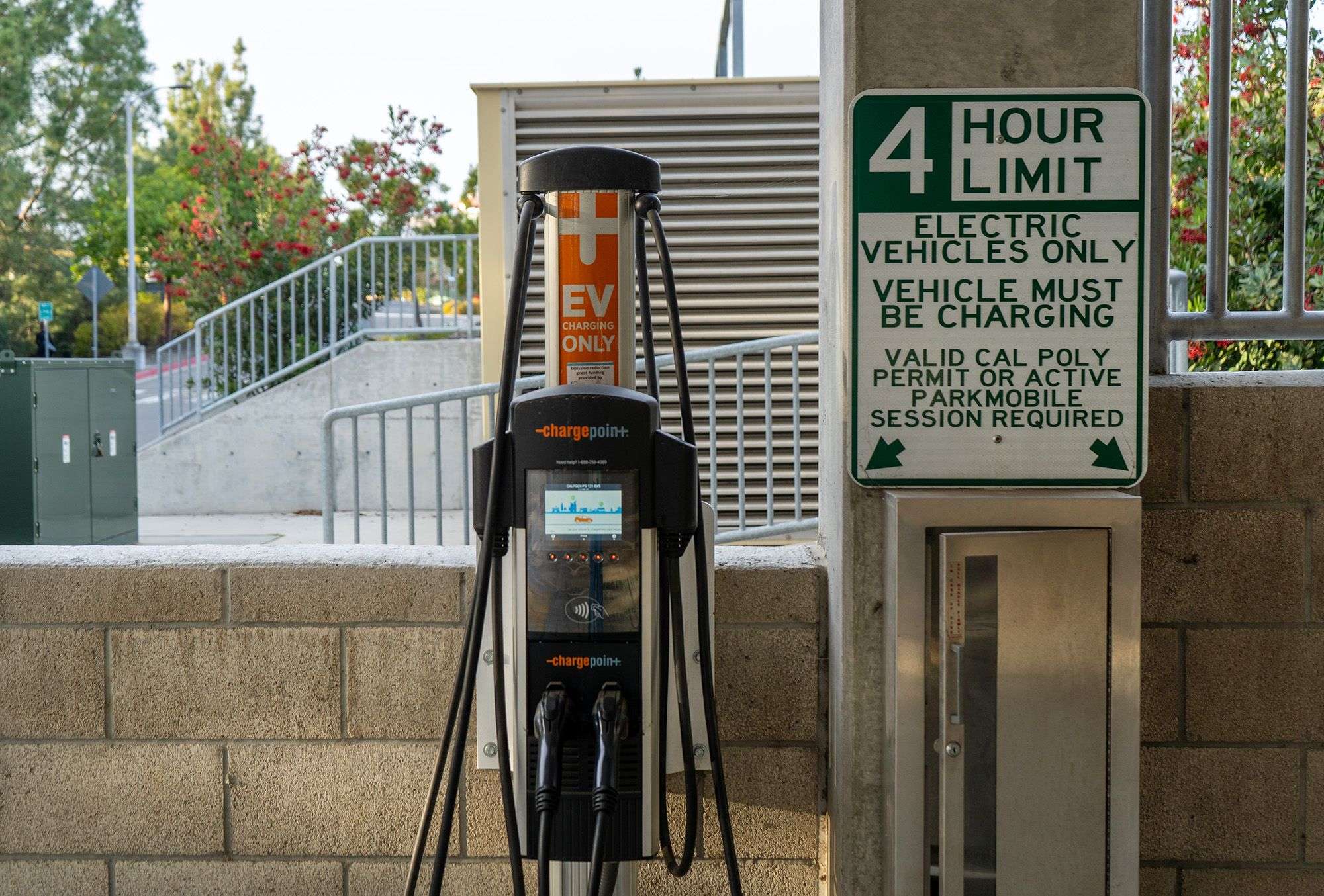 Electric vehicle charging station with a sign reading "4 hour limit, electric vehicles only, vehicle must be charging.