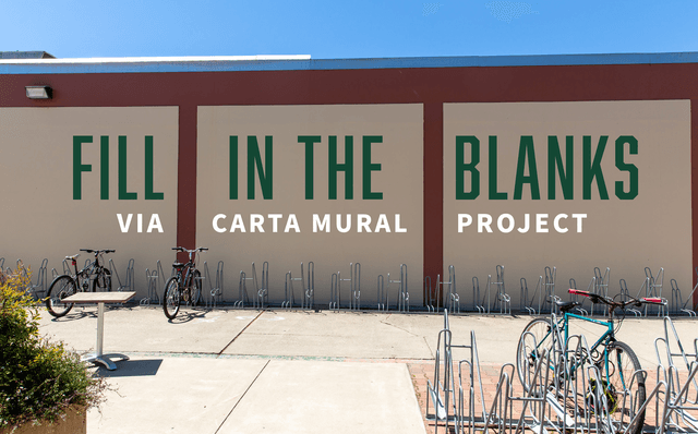 Fill in the blanks via Carta Mural Project painted on a beige wall behind a bike rack with bicycles.