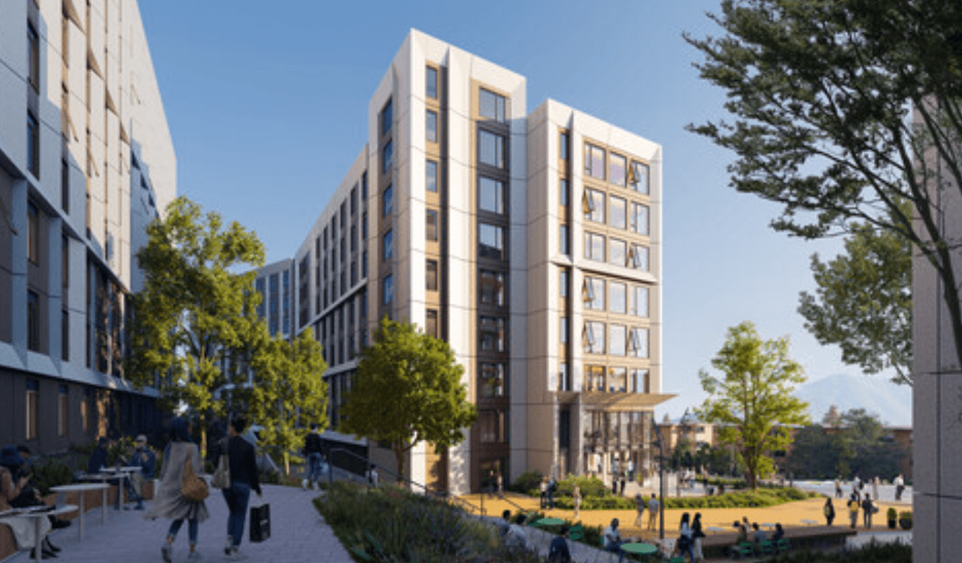 Modern multi-story building with people walking and sitting around a plaza with trees and outdoor seating.