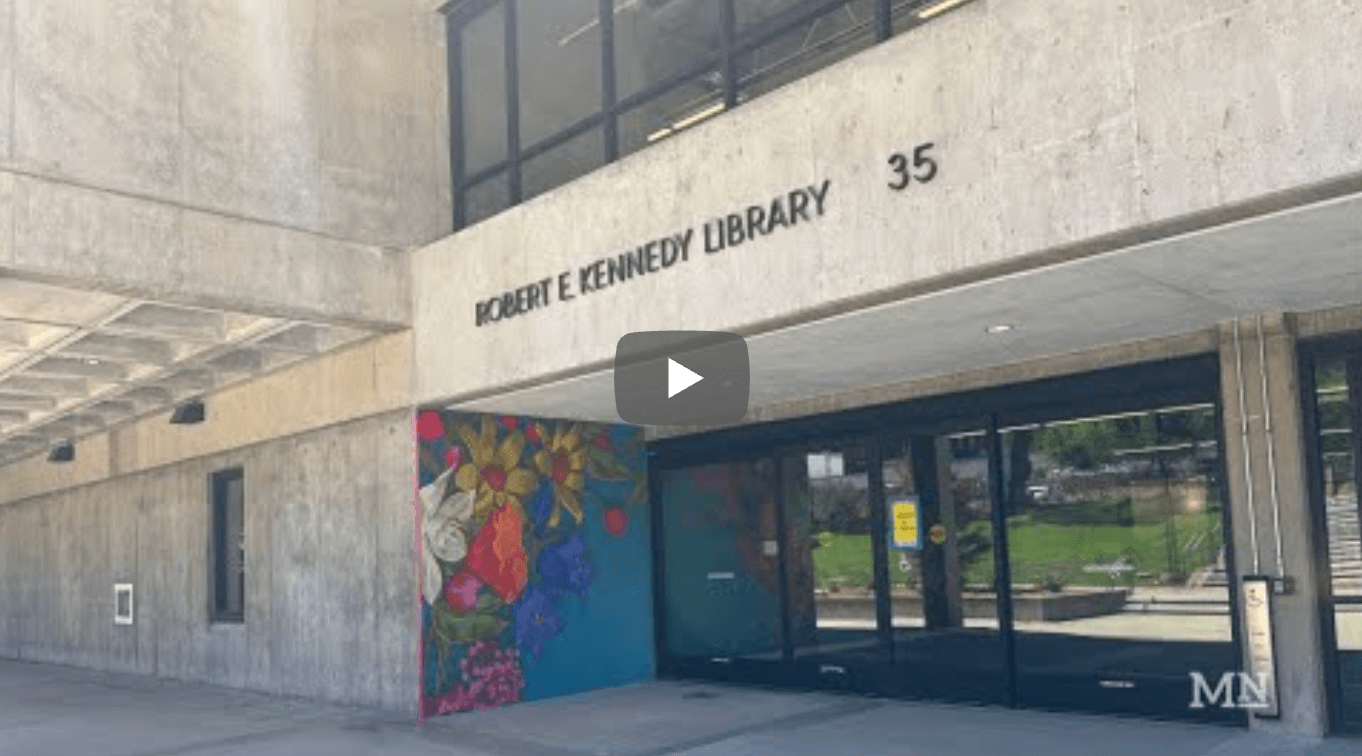 Entrance of Robert E. Kennedy Library with a colorful floral mural painted beside the sliding glass doors on the concrete exterior.